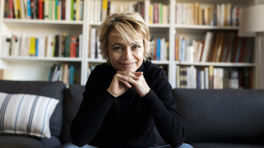 Eine Frau sitzt auf einem Sofa vor Bücherregalen.